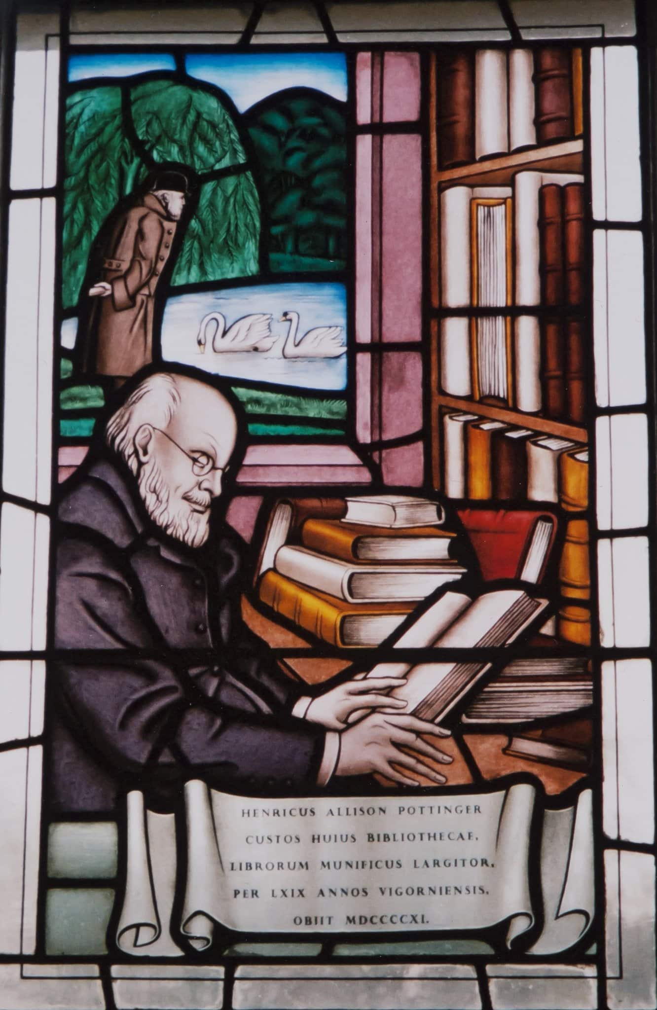 Photograph of a stained glass window. In the foreground Pottinger reads, surrounded by books. In the background he watches two swans on the lake.