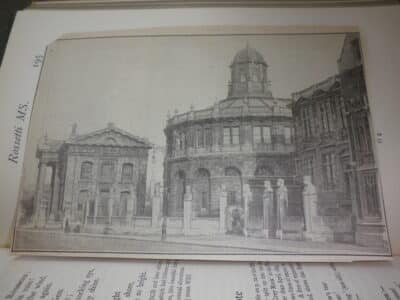 Newspaper clipping showing Sheldonian Theatre with heads on pedestal outside.