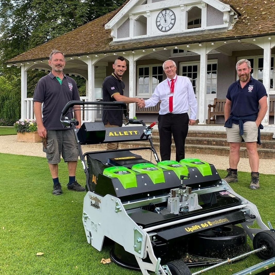 Four staff members with a battery powered mower