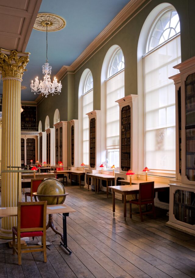 Library interior with large arched windows and wooden desks