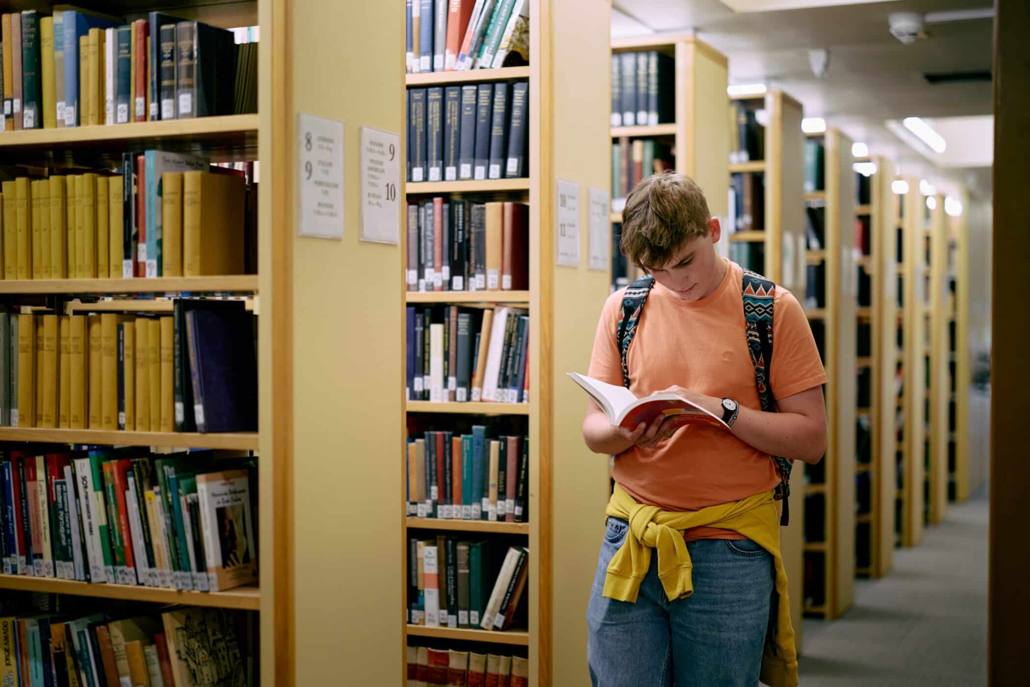 Student reading and walking in library