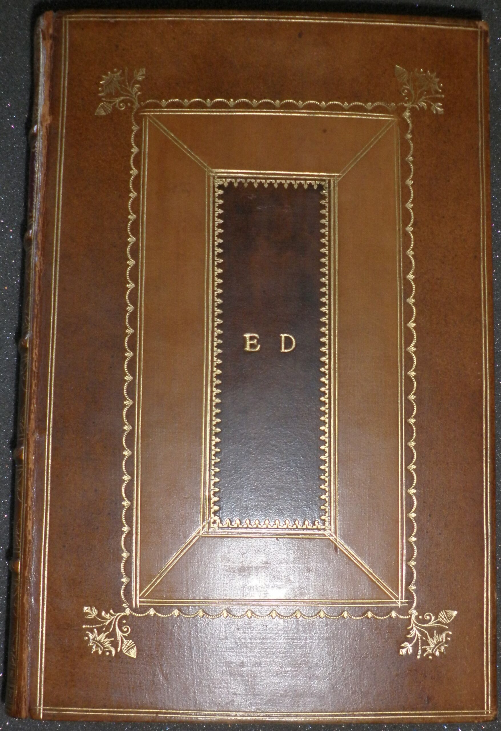 Image of a leather bound book, decorated with gold tooling and with the initials E.D. embossed in gold on the central panel.