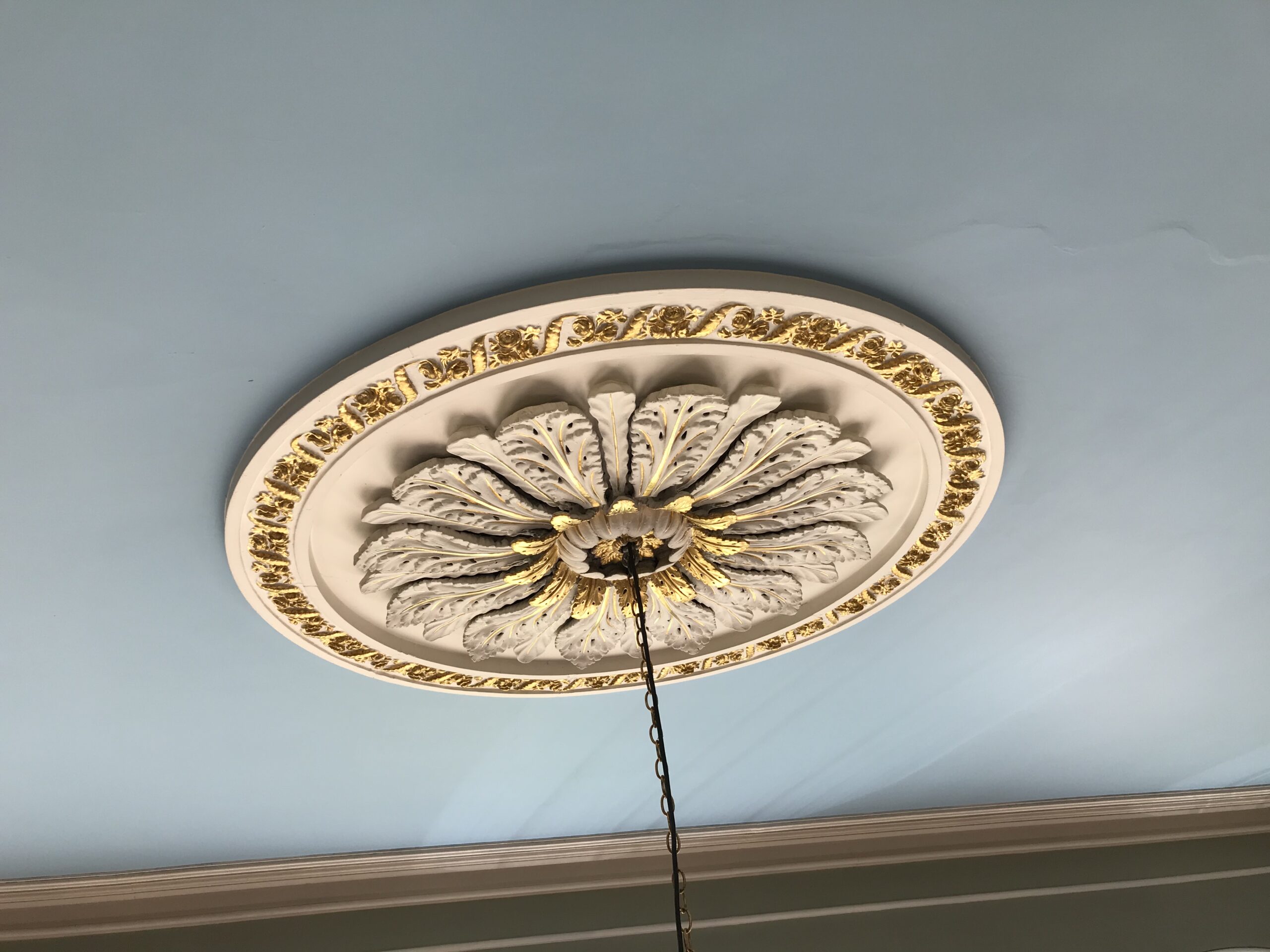 A ceiling rose with gilt decoration on a blue ceiling.