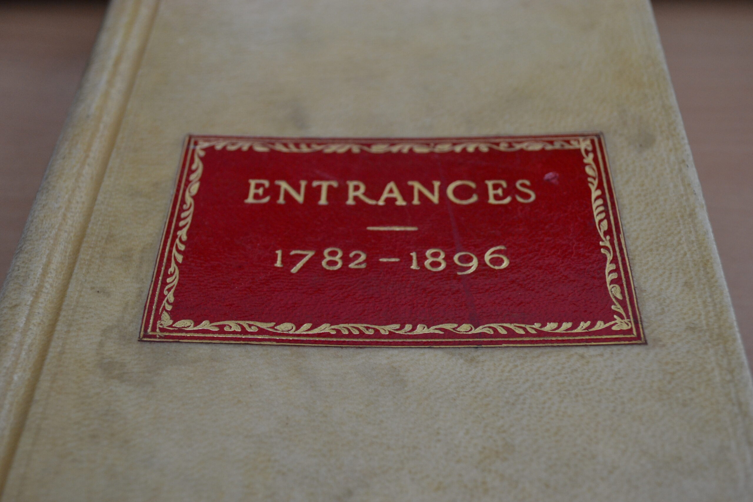 Colour photograph of leatherbound book, which has a red label reading 'entrances 1782-1896'.