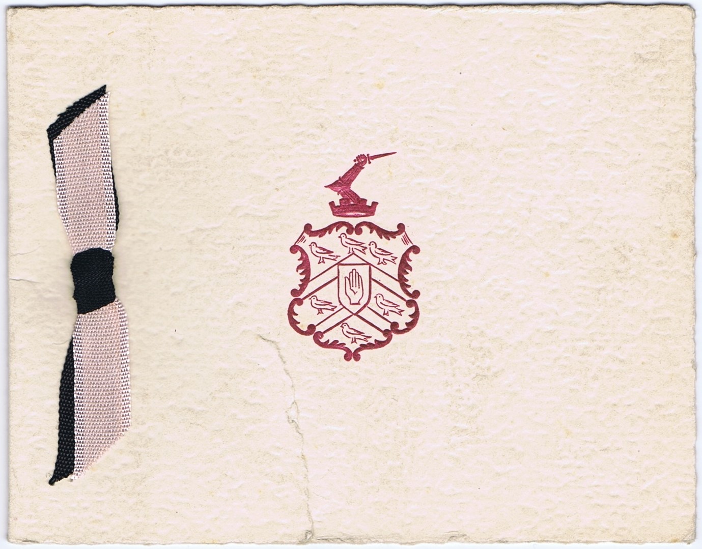 Image of a plain white card with the College crest in red, and a pink and black ribbon on the side.