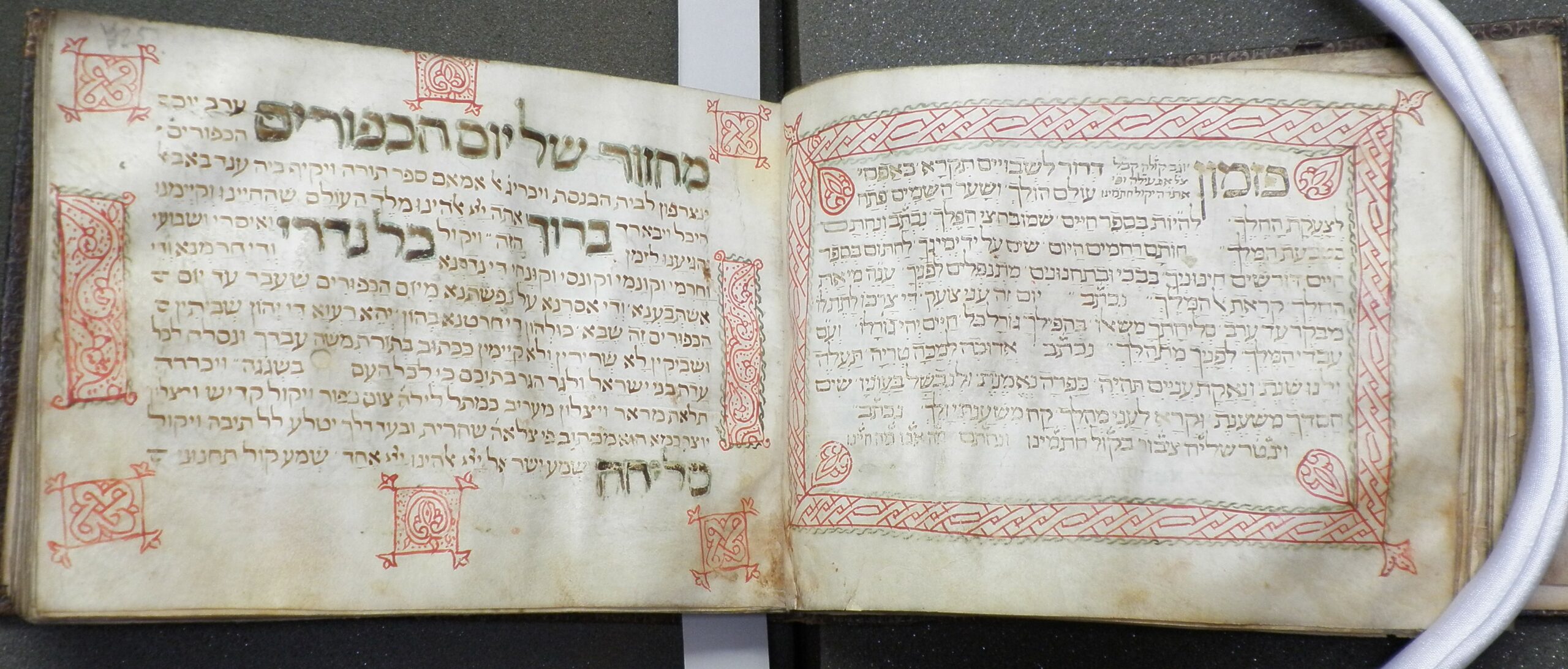 Photograph of Hebrew manuscript text of MS 11, with a decorative border on the right and illuminations on the left in red ink.