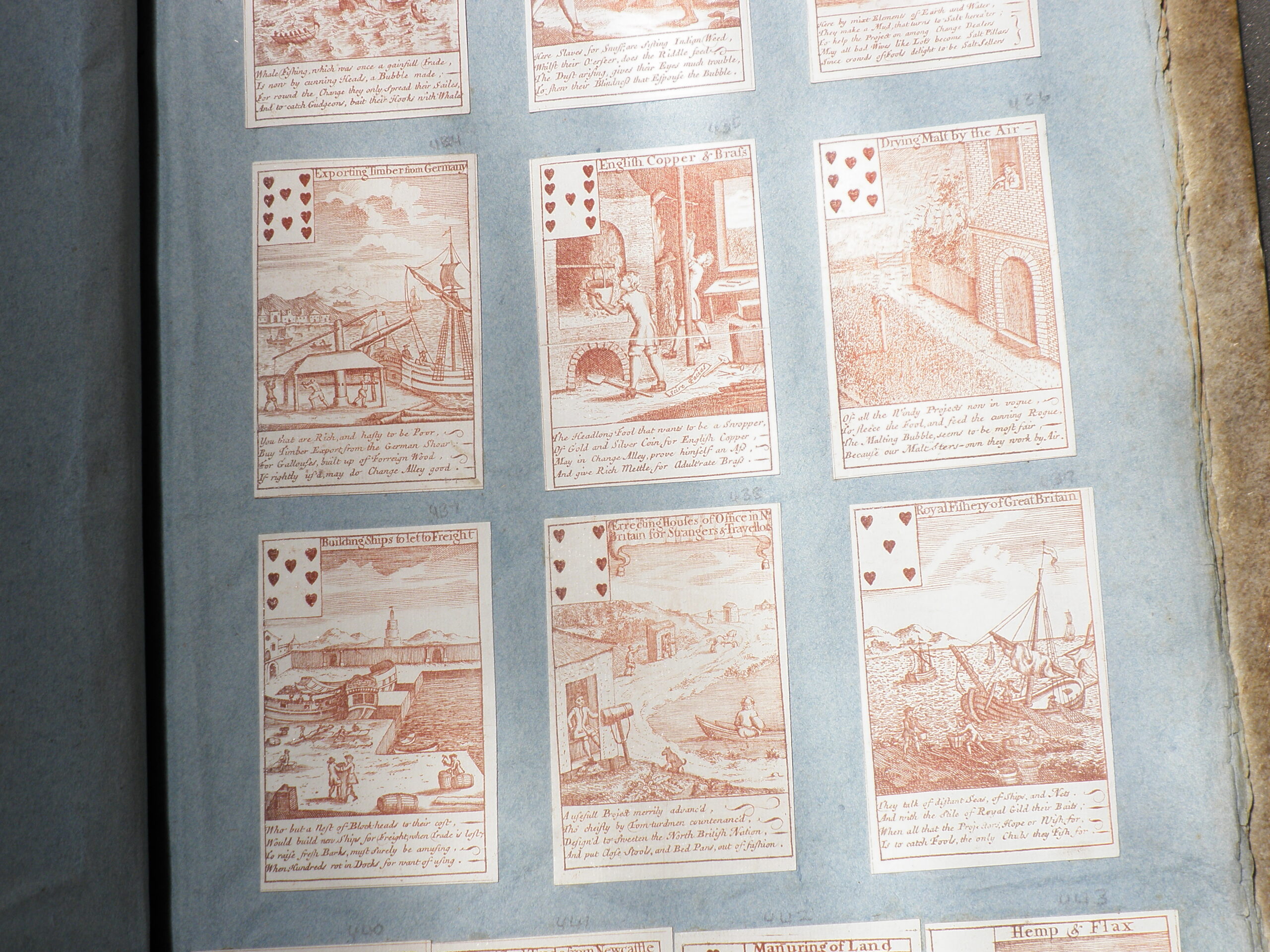 Photograph of several engraved playing cards pasted in an album. Each card has a detailed image.