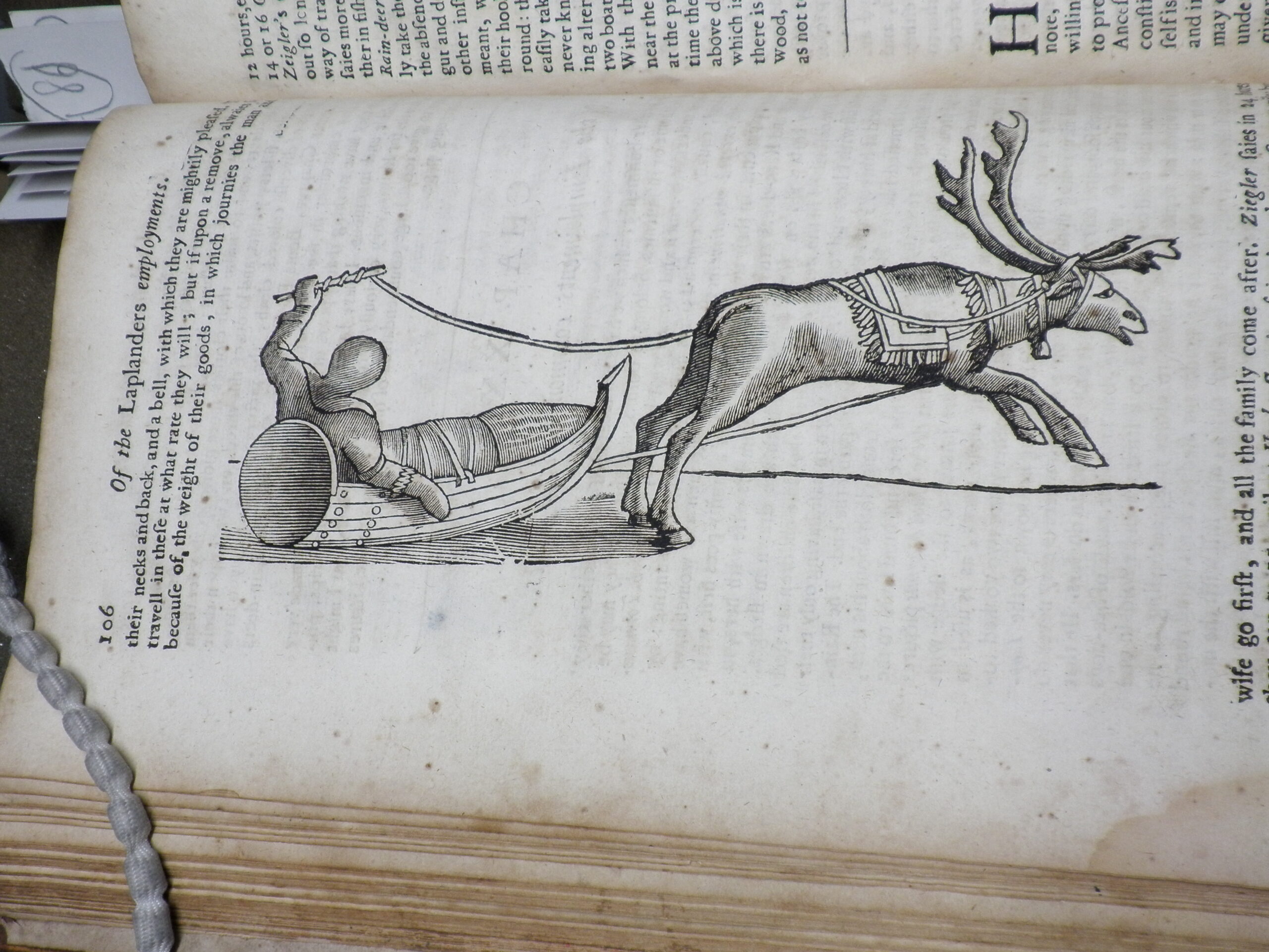 Woodcut illustration of a figure in a sled pulled by a reindeer.