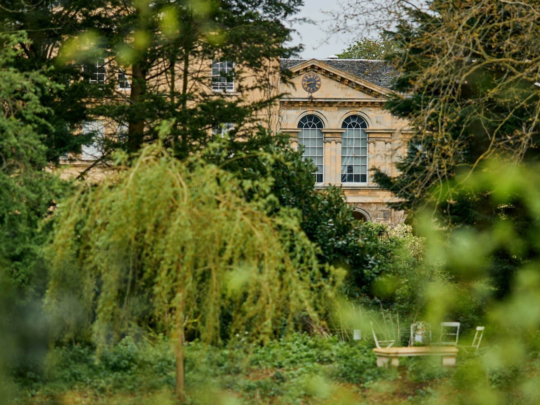 Stone building with arched windows glimpsed through trees