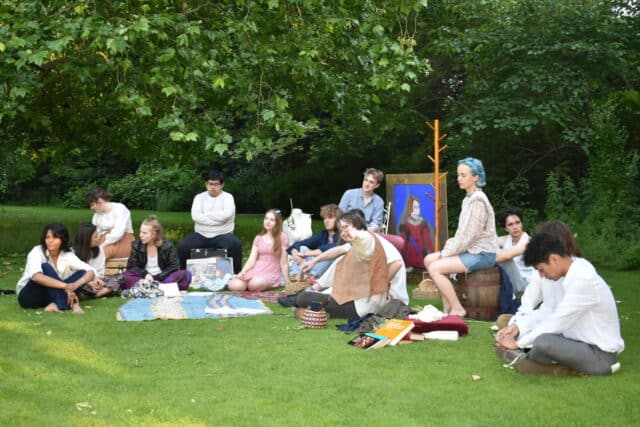 Actors sat in a group on the lawn