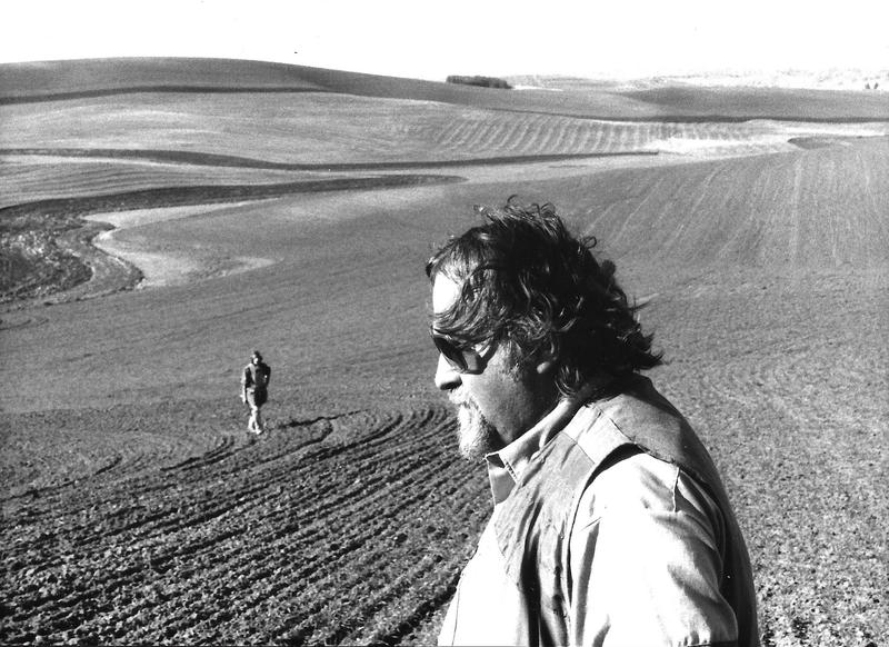 Black and white photograph of two people standing in a ploughed field