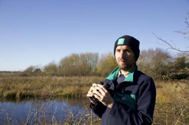Brian Briggs at a wetland with binoculars