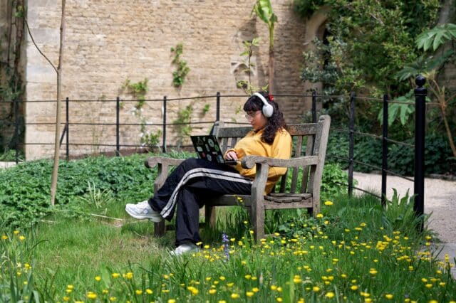 Student working at a laptop on a bench